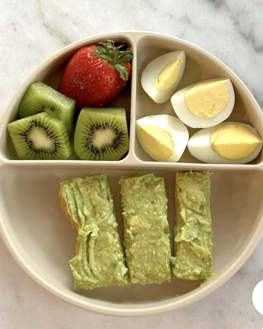 Assiette pour bébé avec fruits, œuf et tartines à l'avocat